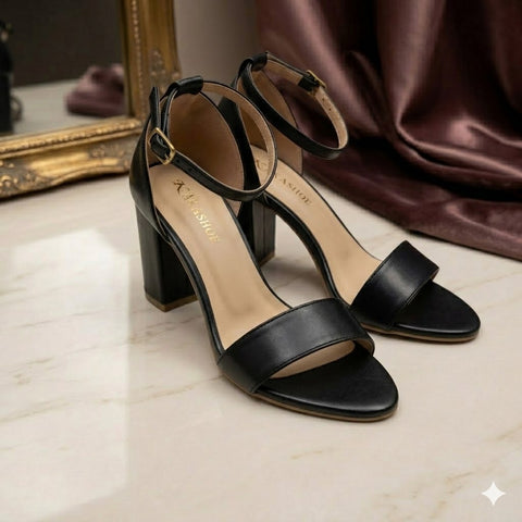 Black high-heeled sandals on a light surface with a mirror and fabric in the background